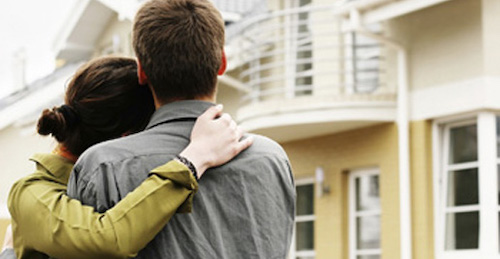 couple in  front of one-family house in modern residential area