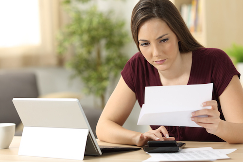 Attentive woman calculating accountancy sitting in a desk at home