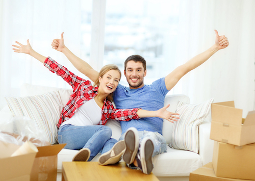 moving, home and couple concept - smiling couple relaxing on sofa in new home