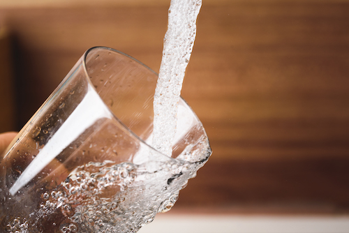Filling glass of water from stainless steel kitchen faucet. Drinking water concept. Austria pure water from mountains.